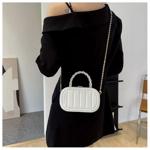 Detail of white quilted box bag with gold chain strap and twisted handle on model