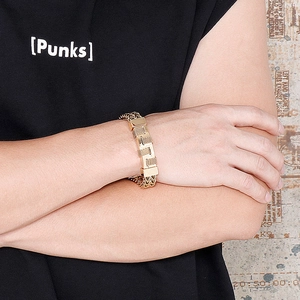 Detail of men's gold hip hop curb chain bracelet with textured metal plate on wrist
