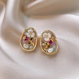 Detailed macro view of floral stud earrings with pearls and crystals on silk background