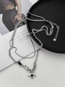 Macro detail of silver layered star necklace with black gemstone inlays and chains