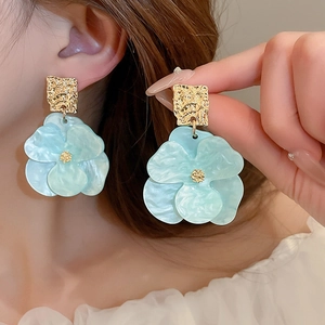 Gros plan de boucles d'oreilles fleurs bleues avec base carrée dorée martelée