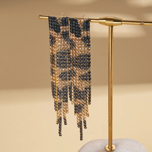 Macro detail of rhinestone leopard print fringe earrings with blue and gold tassels