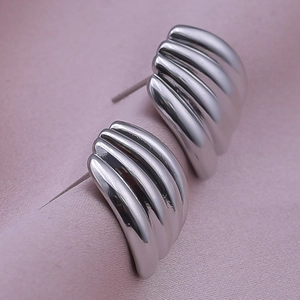 Macro shot of silver 304 stainless steel croissant stud earrings on pink silk fabric