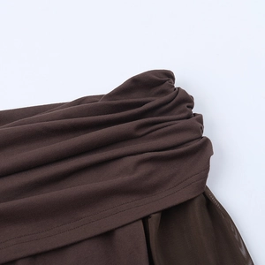 Détail de la couture en maille marron foncé et de la texture plissée d'une robe