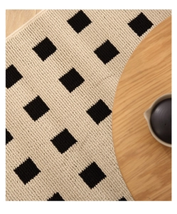 Detailed close-up of woven checkerboard rug texture with high-quality fiber finish
