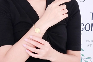 Detailed view of a gold double-layer chain bracelet with pearls and a coin pendant