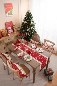 Detail of red Christmas table runner with deer patterns and tassels in a festive setting