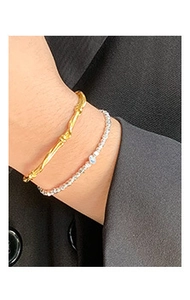 Close-up of gold twist bangle and silver bead bracelet on model in black suit