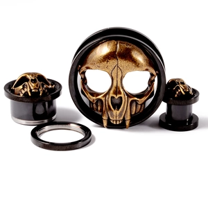 Macro detail of bronze skull flesh tunnels and stainless steel screw-on ear gauges