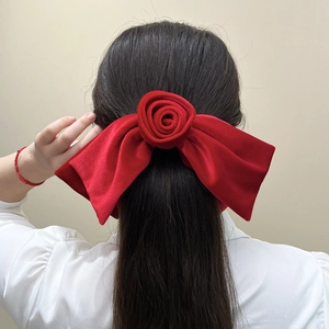 Détail d'un grand nœud en velours rouge avec rose 3D porté sur les cheveux d'un modèle