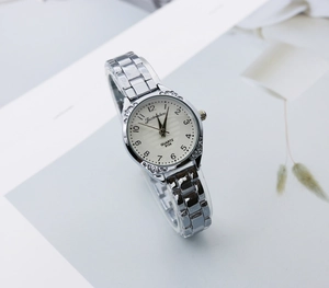 Close-up of a women's quartz watch featuring a carved silver case and numeric dial