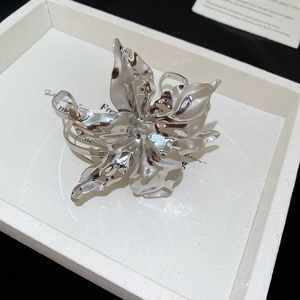 Macro shot of polished silver metal flower jewelry with fluid liquid metal textures