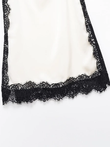 Close-up of white satin camisole featuring intricate black floral lace trim details