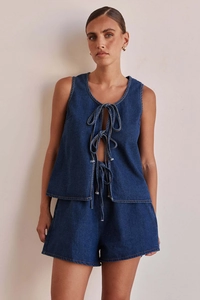 Detail of dark blue denim two-piece set featuring a tie-front sleeveless vest and matching shorts
