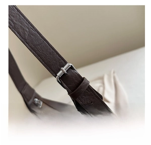 Close-up of adjustable silver buckle on dark brown pebble leather shoulder strap