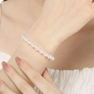 Close-up of elegant oval pearl bracelet with heart detail on a female wrist