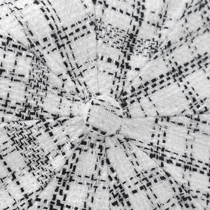 Close-up of black and white plaid tweed fabric texture with decorative top button