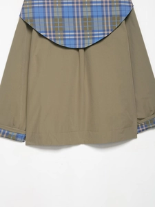 Dettaglio della giacca verde oliva con patchwork a quadri classici blu e marroni
