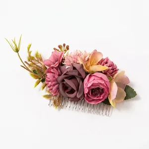 Close-up of handmade floral hair comb with pink fabric roses and green foliage detail