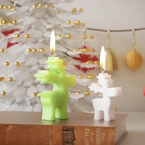 Christmas elk candles in green and white colors placed on books with festive background