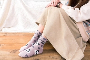 Close-up of purple knit socks with panda and heart patterns and Love Me text detail