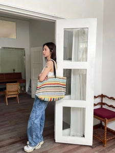 Detail of colorful striped woven tote bag with durable black faux leather straps