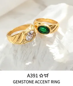 Detail of gold-plated paperclip rings featuring a white zircon and a green oval gemstone