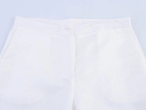 Detailed view of white high-waisted pants featuring button closure and side pockets