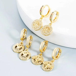 Detailed view of gold hoop earrings with rhinestone tree of life and bee pendants