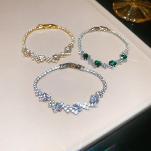 Detailed close-up of oval zircon clasp bracelets in gold and silver with green stone inlay