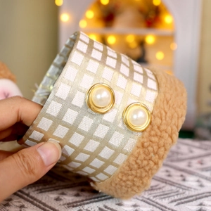 Vista macro di una scatola decorativa a quadri dorati con bottoni di perle e peluche