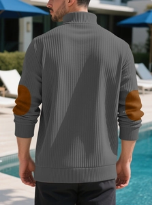 Detail view of men's gray knit sweater featuring brown suede elbow patches in outdoor setting