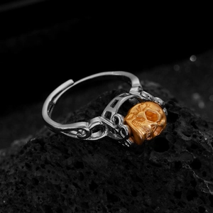 Macro-opname van punk doodskopring met gouden hoofd en zilveren band op lavasteen