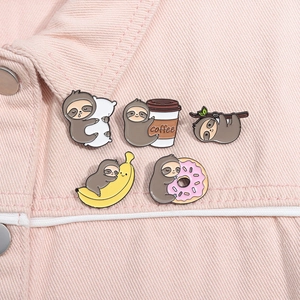 Detail of five cute cartoon sloth enamel pins styled on a pink denim jacket pocket
