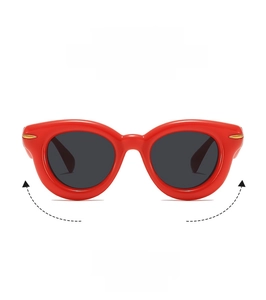 Detail of red thick frame sunglasses with dark round lenses and gold rivet accents