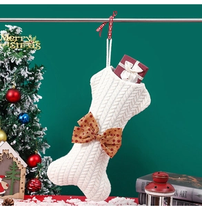 White knitted bone Christmas stocking with red polka dot bow in a festive setting