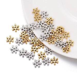 Detailed close-up of 7mm vintage snowflake spacer beads in gold and silver metal alloy