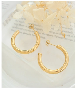 Detailed view of polished 18K gold plated hollow C-shape hoop earrings on a display stand