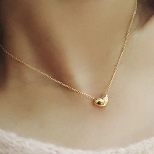 Elegant gold heart pendant necklace for women shown on a model neck in a close-up shot