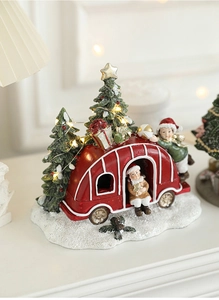 Miniature red camper and green Christmas trees with LED lights on a snowy resin base
