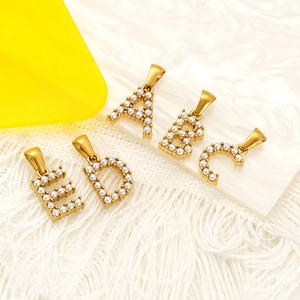Pendentifs alphabet A-E en acier titane doré et perles sur fond en peluche blanc luxueux