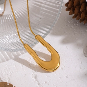 Gros plan du collier doré en forme de U avec chaîne serpent sur fond décoratif