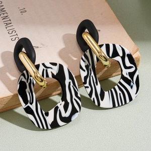Detailed shot of retro zebra pattern acrylic earrings on a vintage book backdrop