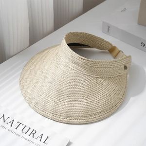Detail of beige straw sun visor with fine woven texture and metal buckle on wide brim