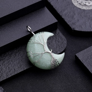 Macro shot of green crystal moon pendant with silver wire-wrapped tree of life on stone