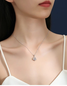 Close-up of a silver hexagram necklace with a sparkling center stone worn on a neck
