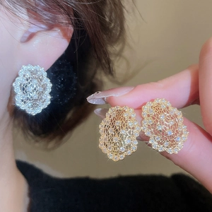 Gros plan de boucles d'oreilles dorées en dentelle ajourée avec zircons scintillants