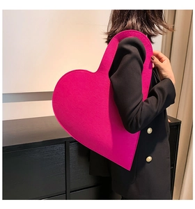 Detail view of a large heart-shaped felt handbag in vibrant magenta for stylish women
