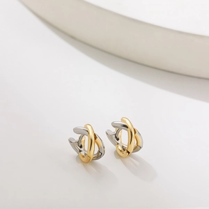 Macro detail of intertwined gold and silver rings showing a polished cross texture
