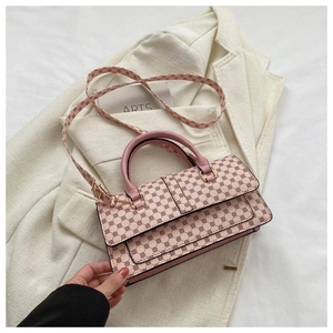 Detail of pink rectangular handbag featuring brown circular patterns and gold hardware
